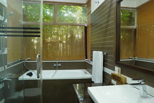 A modern bathroom with a glass-enclosed shower, a bathtub, and a vanity with a mirror.