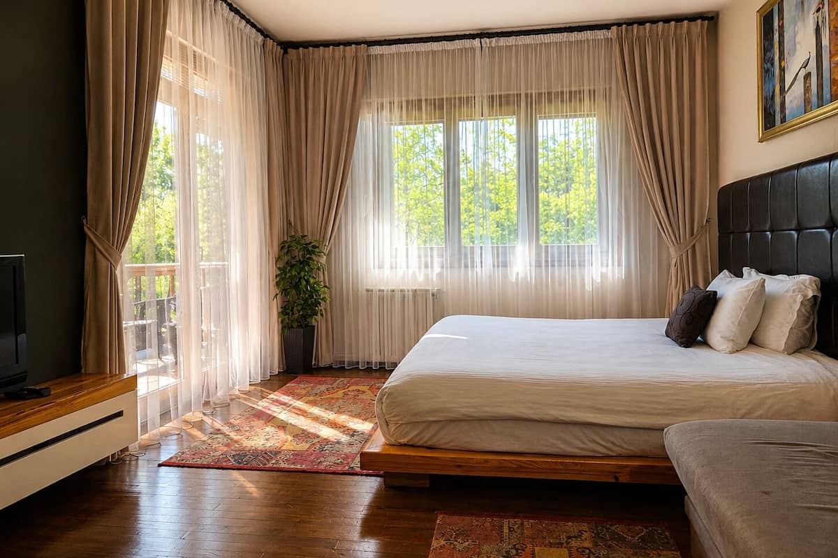 A bedroom with a bed, a TV, a plant, and a balcony.
