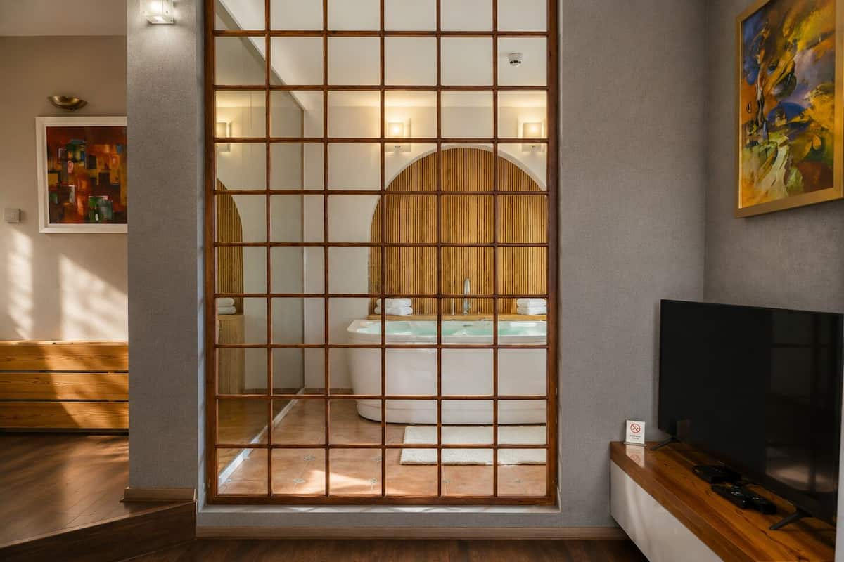 A modern room with a wooden sliding door, a bathtub, a television, and a painting on the wall.