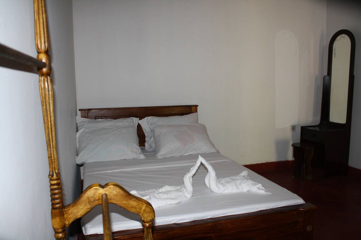Un lit bien fait, avec une tête de lit en bois et un miroir accroché au mur.