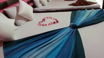 A hotel room with two beds, one with a blue draped bedspread and the other with white bedding and pillows.