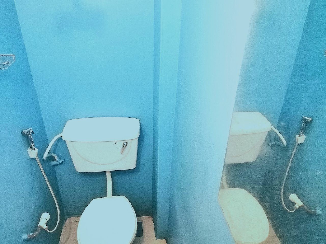 A small, enclosed bathroom with a white toilet and a wall-mounted tank.