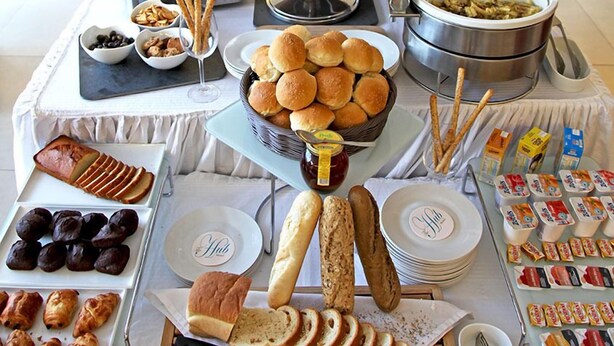 A buffet with various food items including bread, pastries, and condiments. - The Hub Hotel (Freetown)