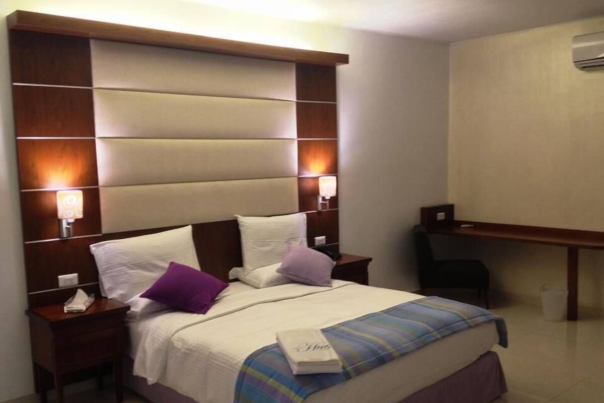 A hotel room with a large bed, two bedside tables, a desk, and a chair.
