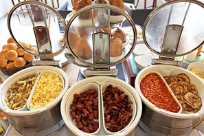 A buffet with multiple food options including pasta, scrambled eggs, bacon, beans, and fried eggs. - The Hub Hotel (Freetown)