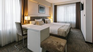 A hotel room with a bed, a desk, a chair, and a bench. - Hotel Heritage (Belgrade)