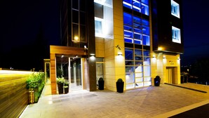 A modern building with a glass facade, a wooden entrance, and a paved walkway. - Hotel Heritage (Belgrade)