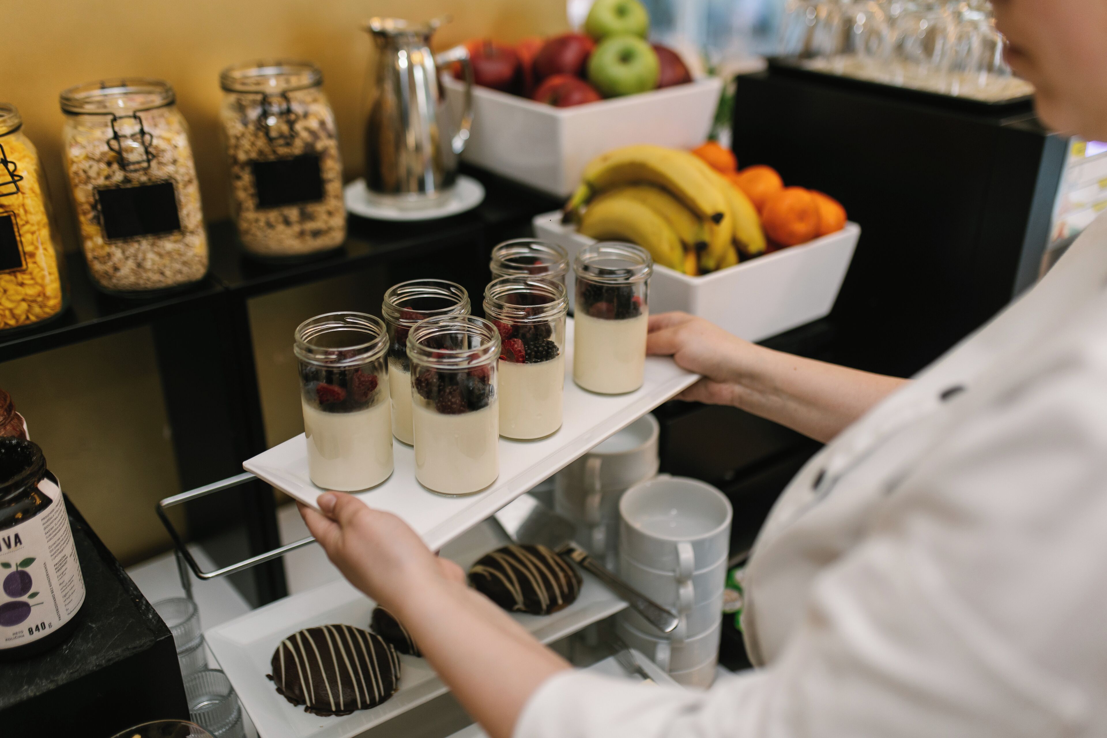 Un plateau avec des pots de nourriture et un saladier de fruits.