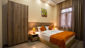 A hotel room with a large wardrobe, a bed with orange bedding, two bedside lamps, and a painting on the wall. - My Hotel Yerevan (Yerevan)