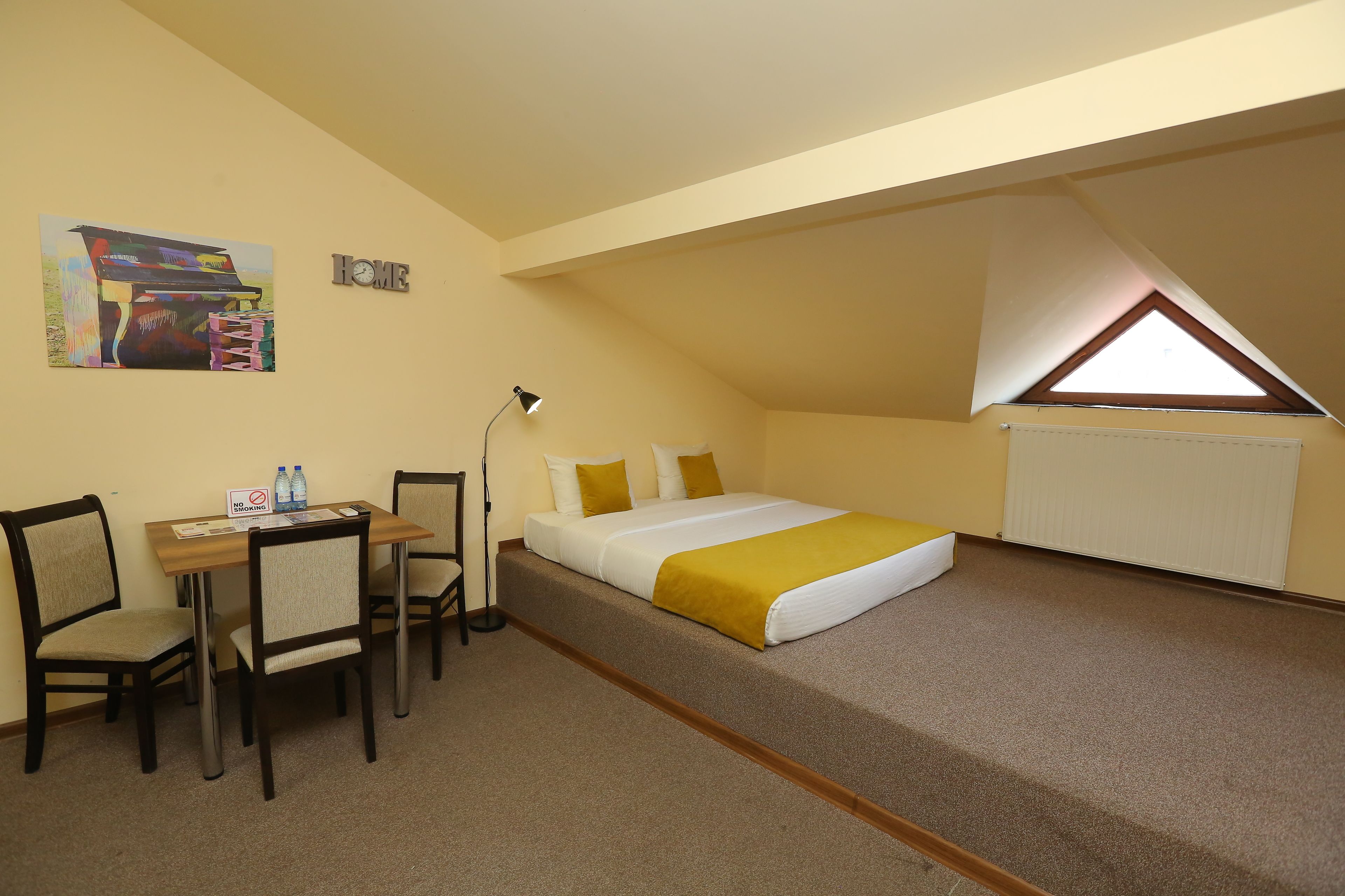 Une chambre à coucher avec un lit, un bureau, deux chaises, une lampe et un tableau au mur.