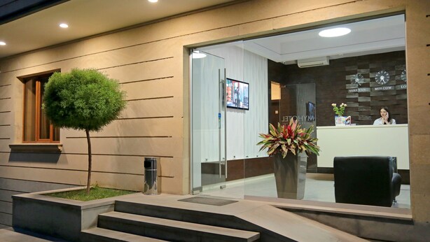A modern hotel reception with a glass door, a reception desk, and a clock on the wall. - My Hotel Yerevan (Yerevan)
