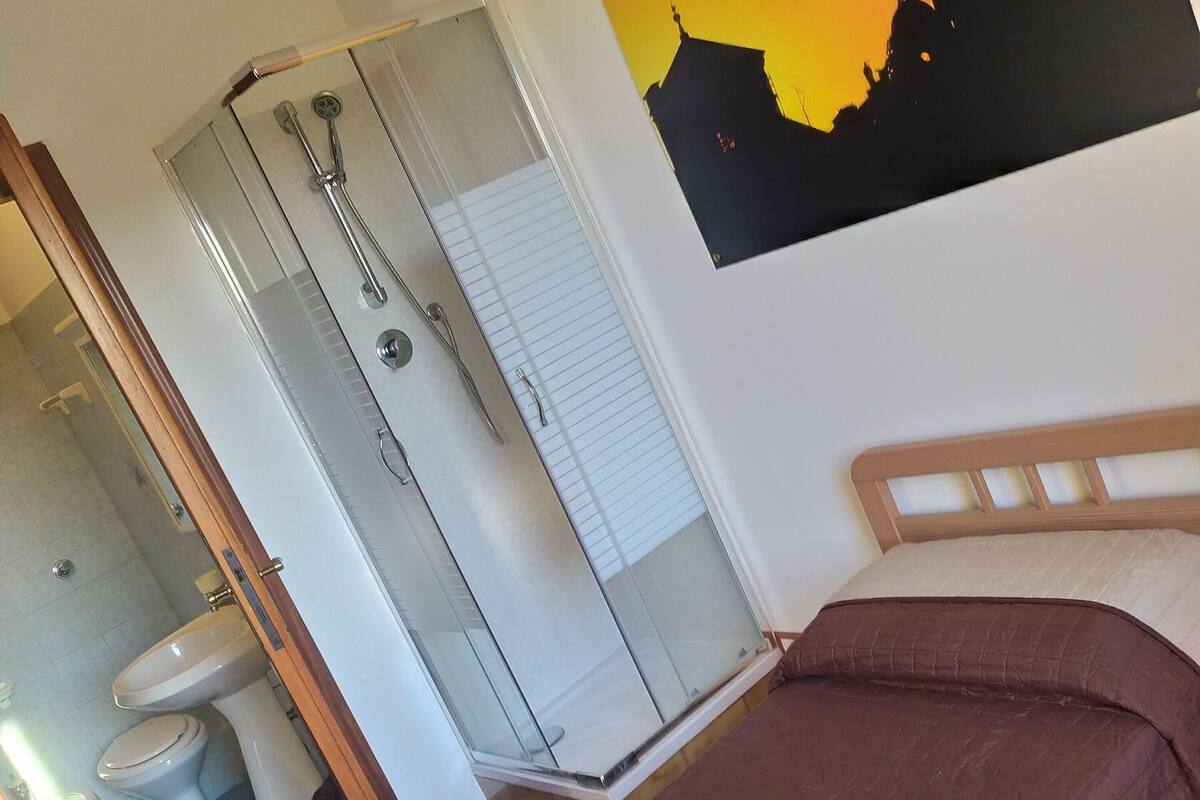 Una camera da letto con un letto, un bagno con il water e una doccia.
