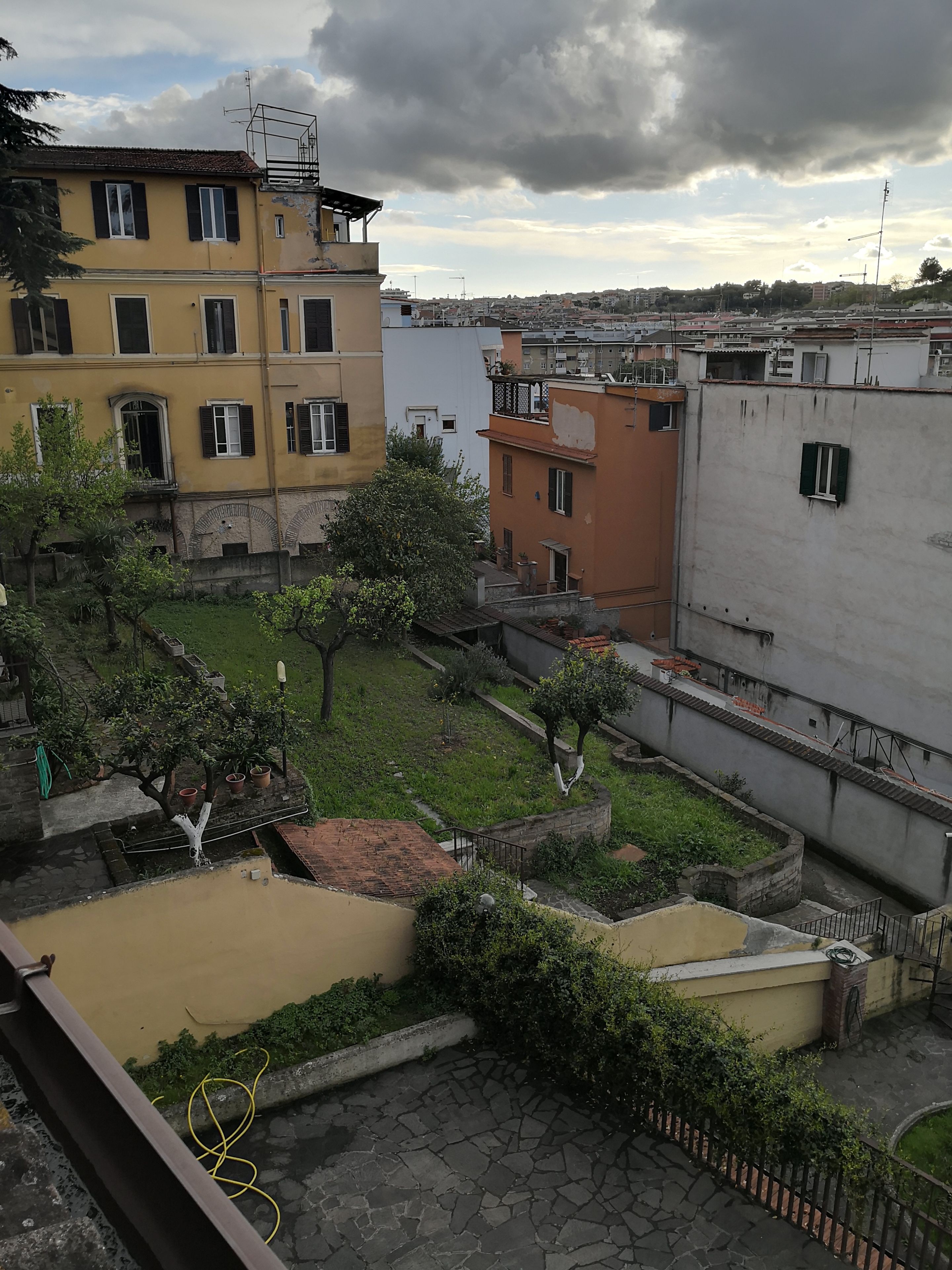 Un patio con un pequeño estanque, rodeado de edificios con balcones y una mezcla de estilos arquitectónicos.