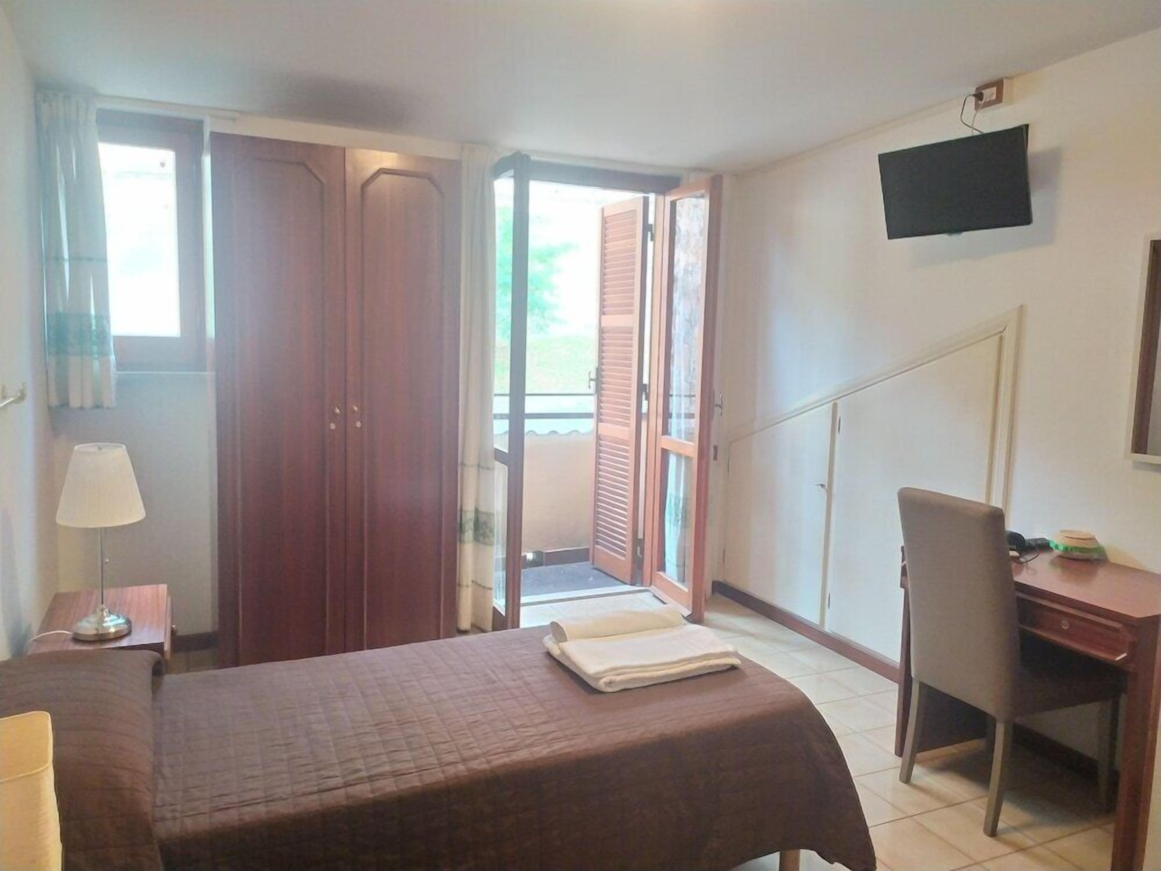 Une chambre d’hôtel avec un lit, un bureau, une chaise, une télévision et une fenêtre.