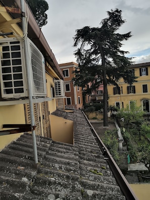 Zona residencial con una escalera que lleva a un edificio equipado con unidades de aire acondicionado.