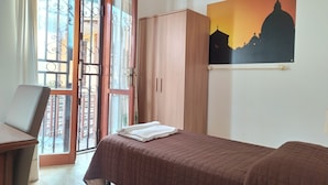 Un dormitorio con cama, armario de madera, escritorio y ventana con cortinas.