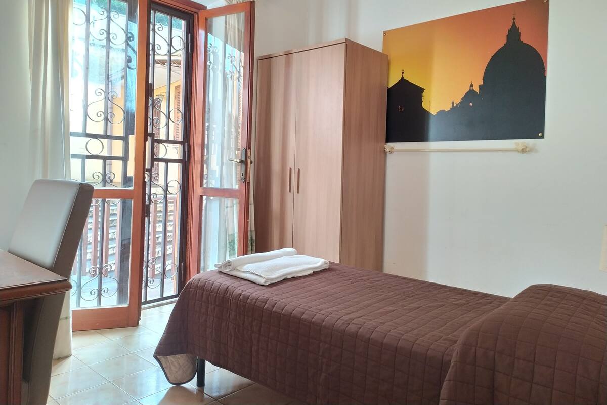 Una camera da letto con un letto, un armadio in legno, una scrivania e una finestra con tende.