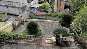 Un patio con pavimento de piedra, rodeado de edificios con balcones y antenas parabólicas.