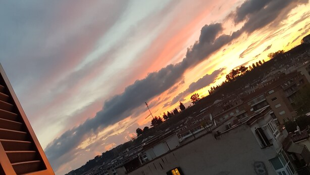 Vista al atardecer desde un balcón con un paisaje urbano de fondo.