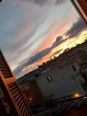 Vista al atardecer desde un balcón con un paisaje urbano de fondo.