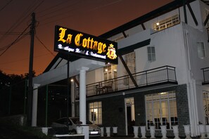 Un edificio de dos plantas con un letrero que dice 'La Cottage Boutique Hotel & Restaurant'.
