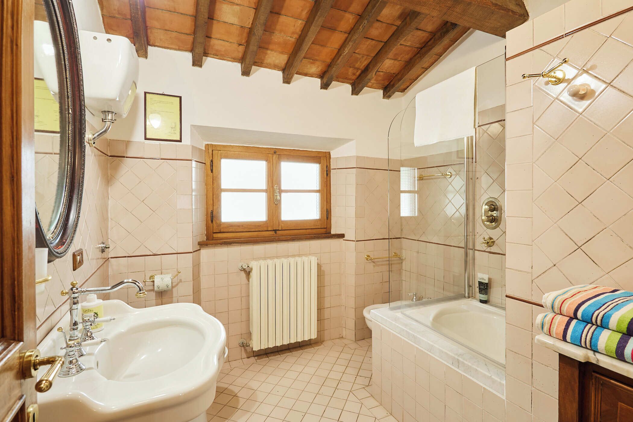 A bathroom with a sink, bathtub, and a window.