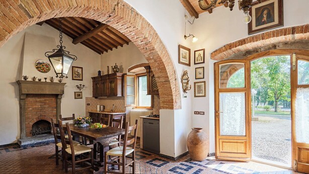 A rustic dining area with a brick fireplace, wooden table, and chairs. - Agriturismo Villa Augusto (Cortona)