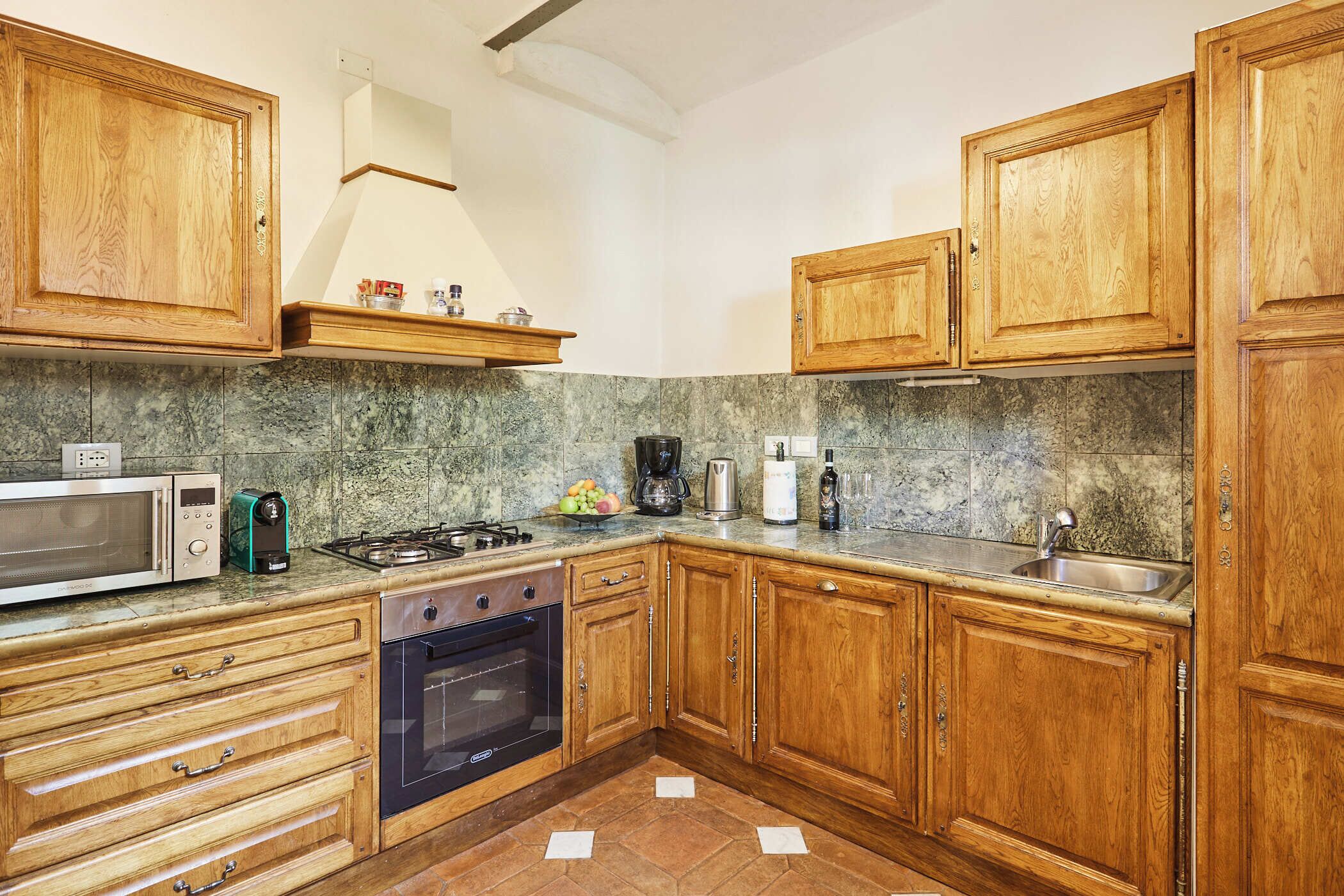 A kitchen with wooden cabinets, a microwave, stove, oven, and granite countertop.