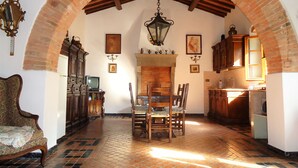 A dining area with a brick fireplace, wooden chairs, and a table. - Agriturismo Villa Augusto (Cortona)