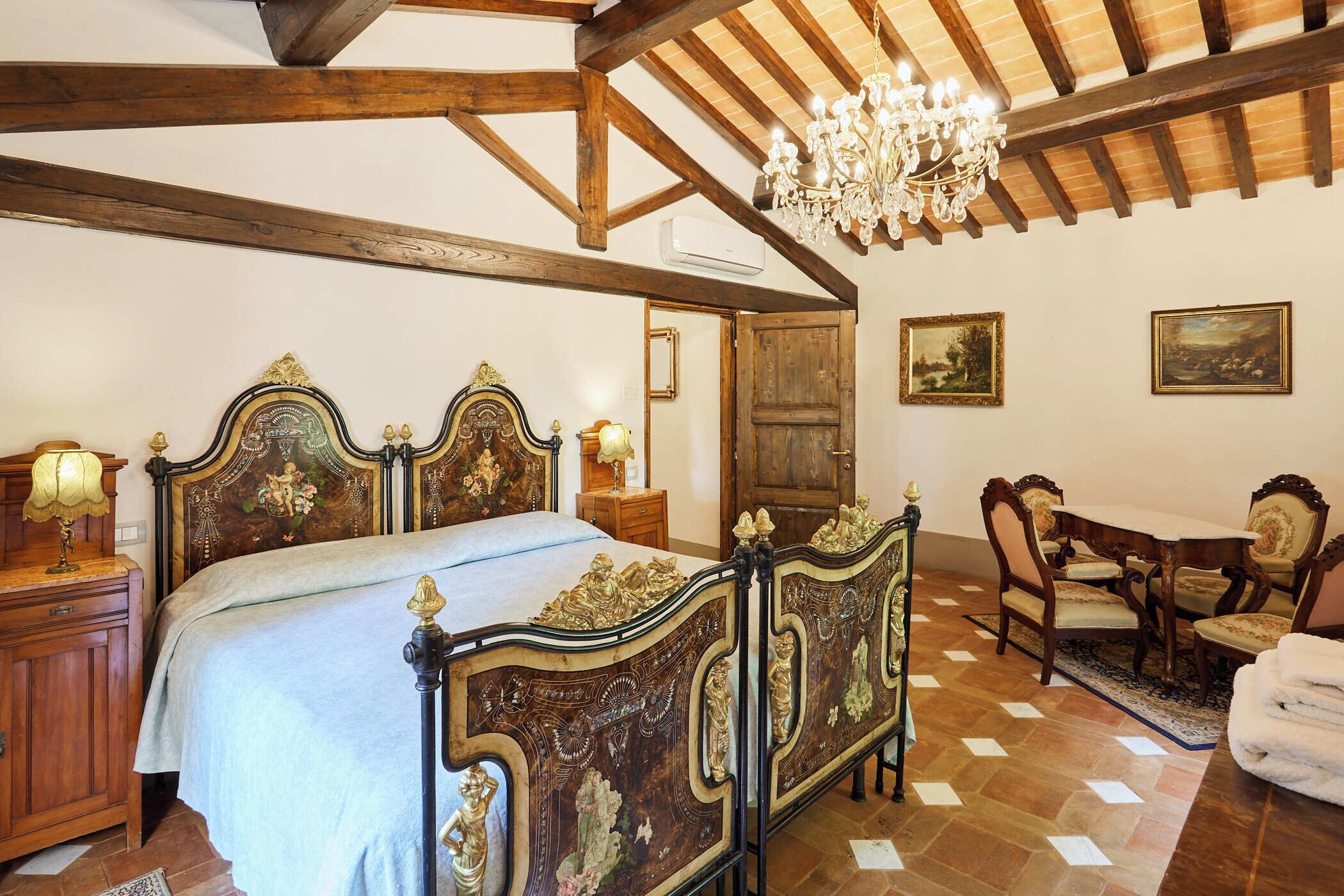 Un dormitorio con una cama grande y elaborada, muebles de madera y un candelabro.