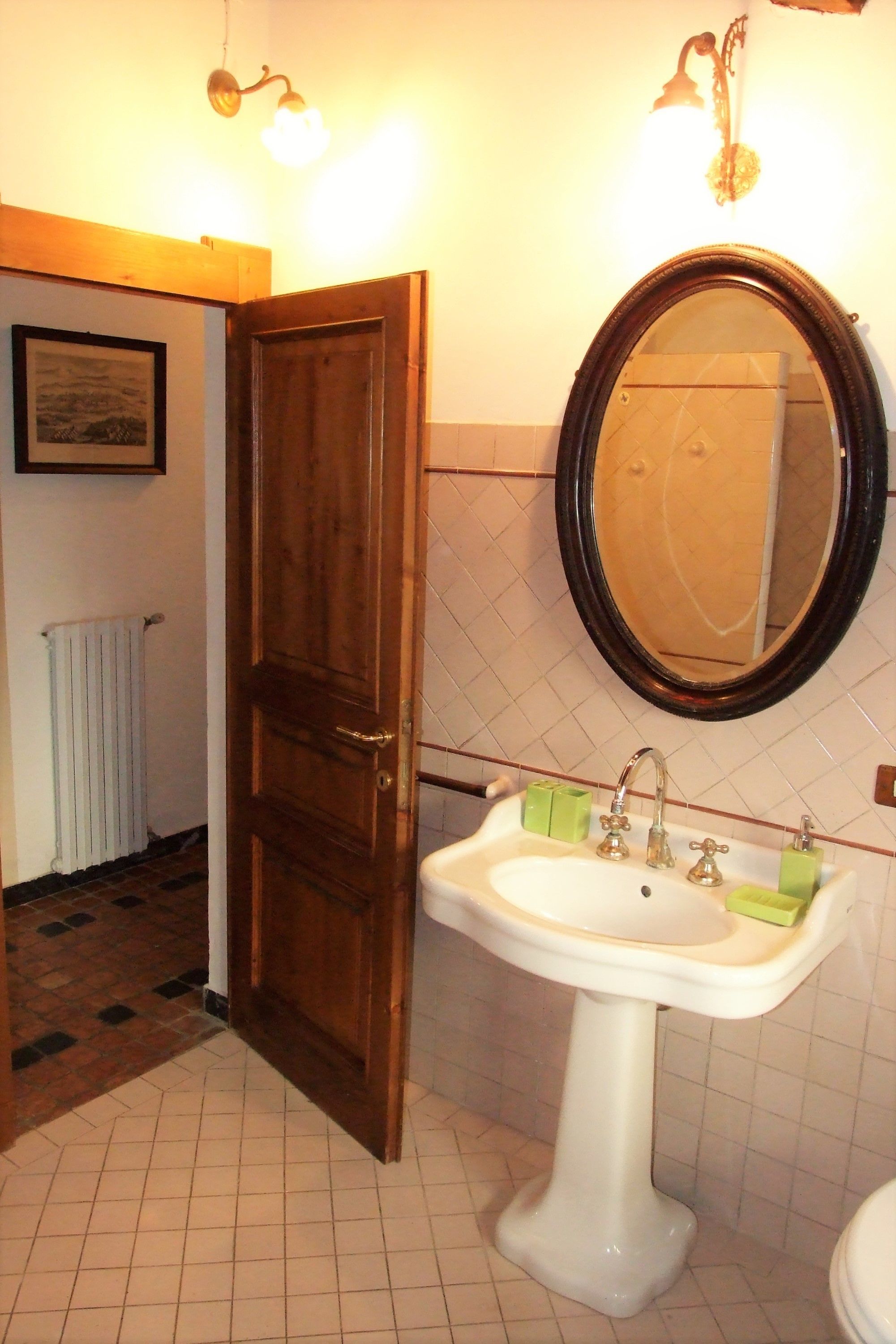 Een badkamer met een wit wastafelmeubel, een houten deur en een spiegel.