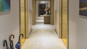 A hallway with a tiled floor, wooden cabinets, and a wall-mounted umbrella rack. - Tifani Luxury Rooms 2 (Split)