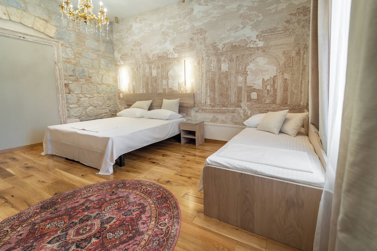 Una habitación con dos camas, una pared de piedra y un mural.