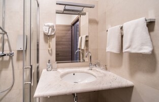 Ein Badezimmer mit Waschbecken, Spiegel, Handtuchhalter und Fön.