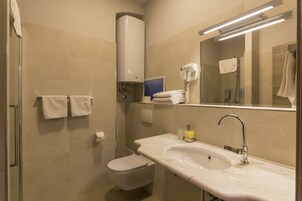 Ein Badezimmer mit Toilette, Waschbecken, Handtuchhalter und Fön.