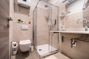 Un baño moderno con cabina de ducha de vidrio, inodoro, lavamanos y espejo.