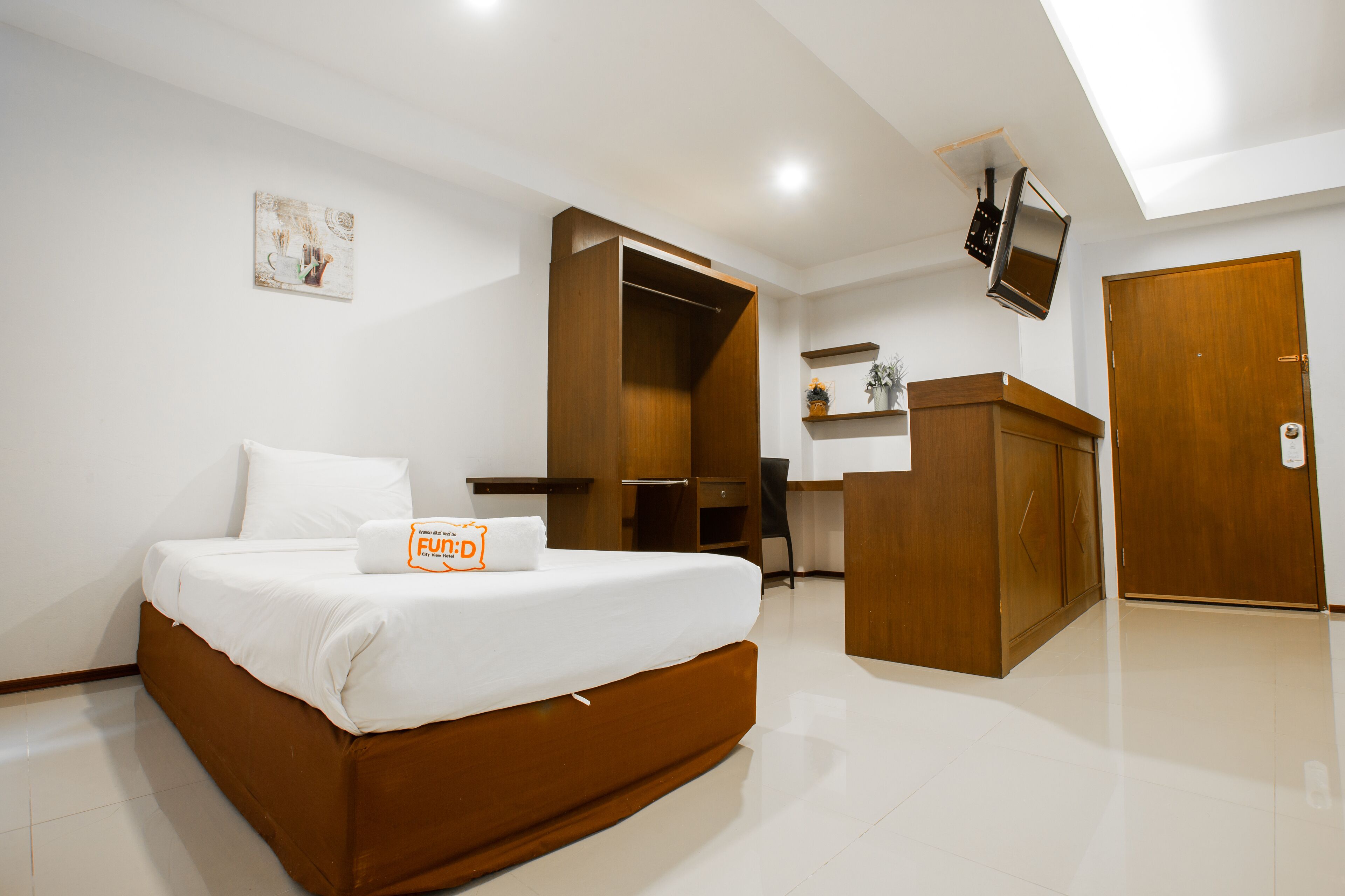 Una habitación de hotel moderna con una cama grande, un escritorio, un armario y un televisor fijado a la pared.