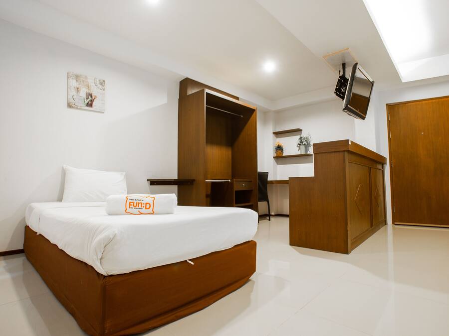 Una habitación de hotel moderna con una cama grande, un escritorio, un armario y un televisor fijado a la pared.