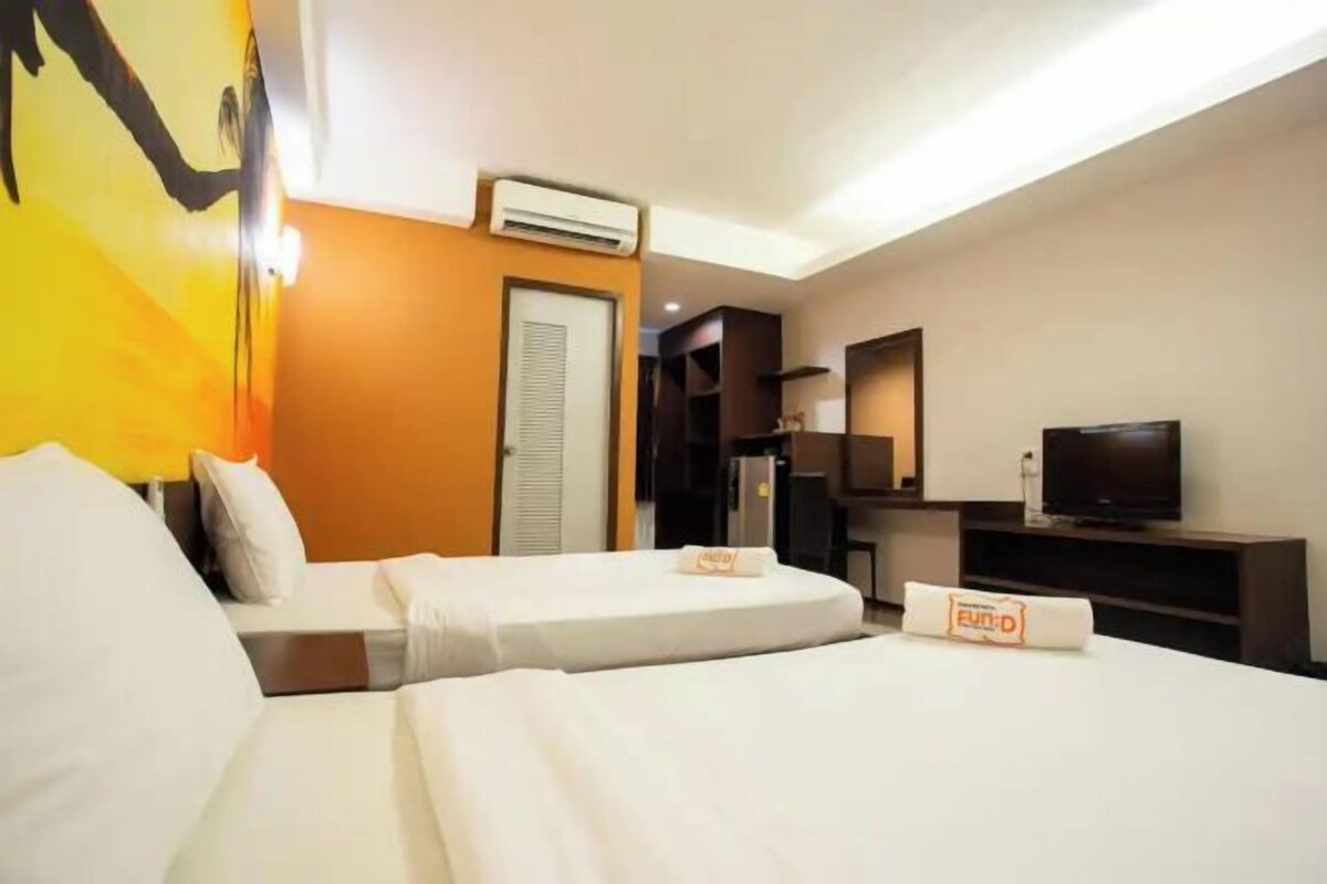 A hotel room with two beds, a television, a minibar, and a door.