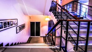 A staircase with a wooden handrail and metal balusters, leading to a door with a light fixture above it. - Fun-D City View (Khon Kaen)