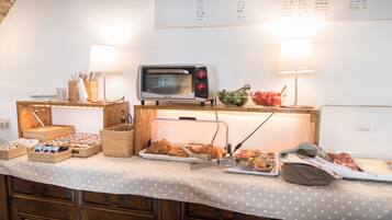 A buffet setup with a variety of food items, a microwave, and a menu board on the wall.