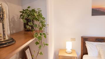 A neatly arranged bedroom with a bedside table, a lamp, a bed, and a wall-mounted picture.