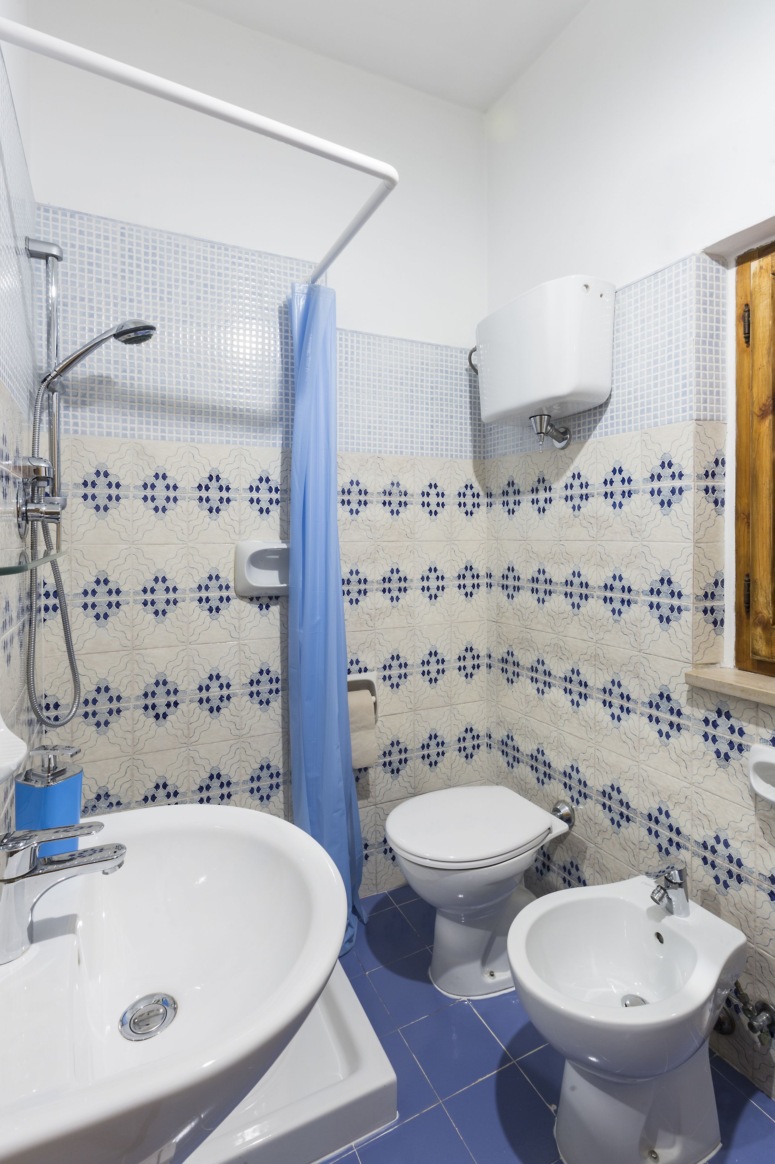 Un baño con lavamanos, dos inodoros, un bidé y zona de ducha.