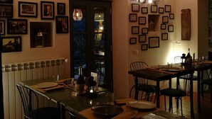 A dining area with a brick ceiling, a long table set for two, and framed pictures on the walls. - Tananei (Marliana)