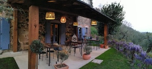 A rustic stone building with outdoor seating and hanging lights.