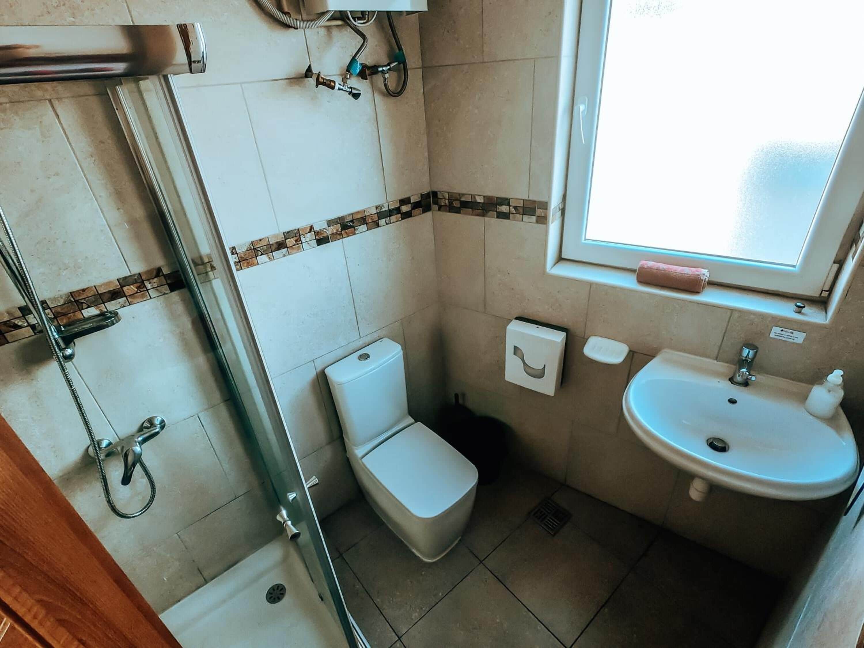 Une salle de bain avec des toilettes, un lavabo et une douche.
