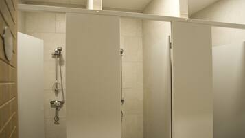 A shower area with a glass partition, a handheld showerhead, and a wall-mounted faucet.