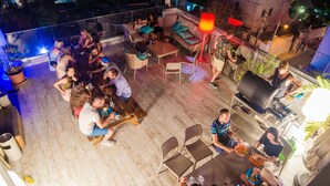 An outdoor patio area with seating, a grill, and a view of the city at night. - Marco Polo Malta Hostel (St. Julian's)