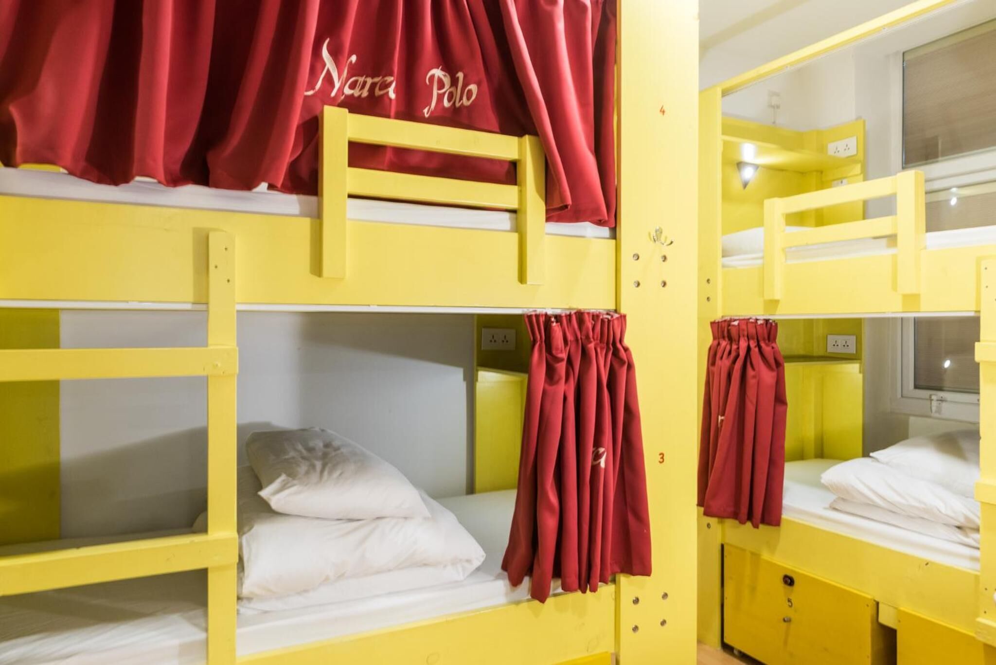 A bunk bed room with yellow beds and red curtains.