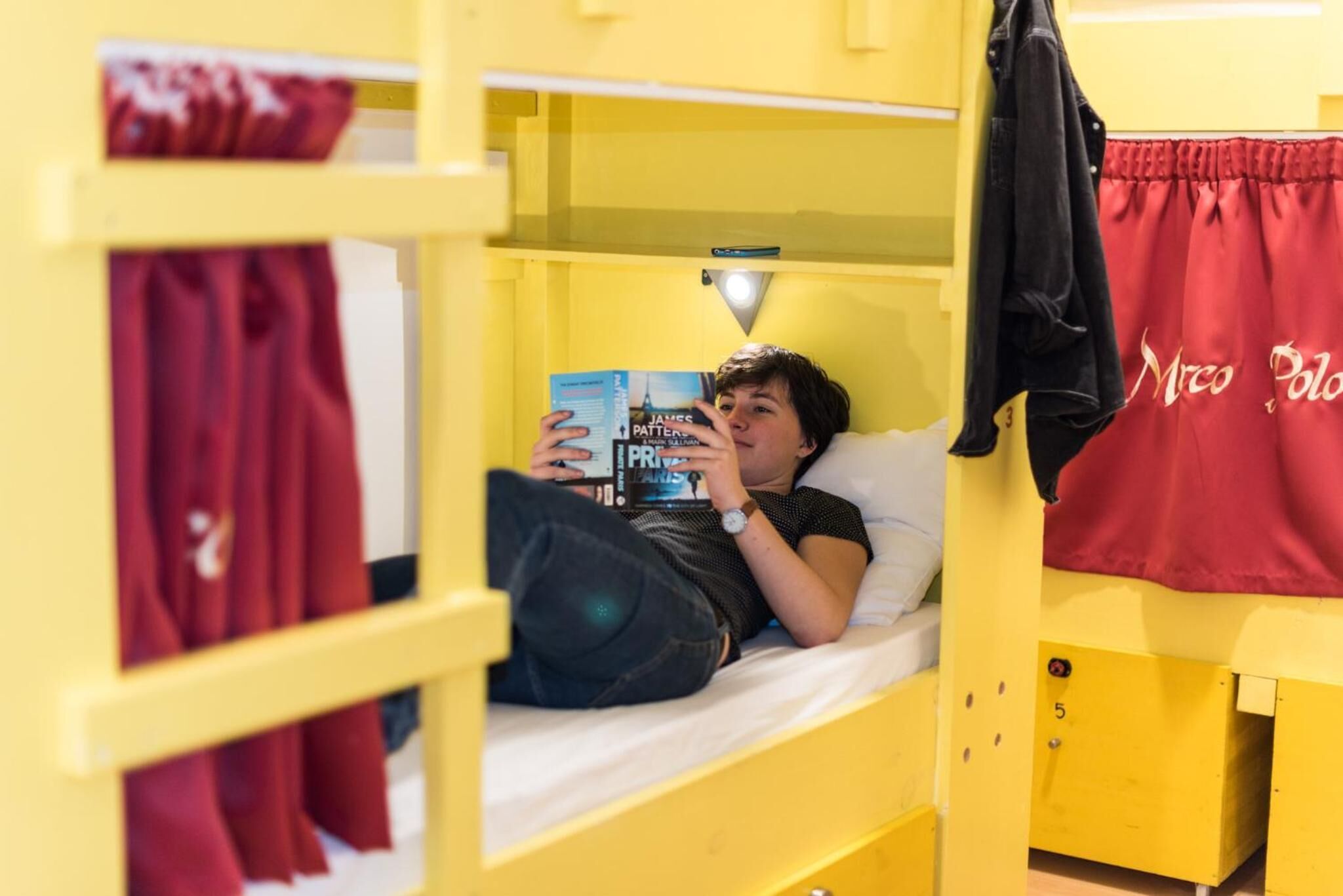 A bunk bed with a person reading a book.
